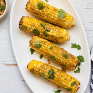 a platter of corn on the cob with cilantro ganish