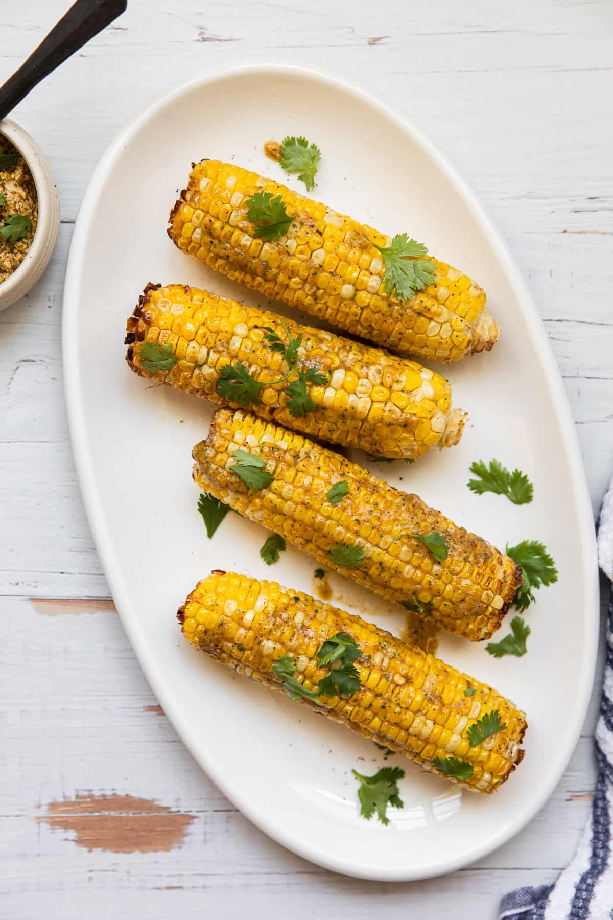 corn on the cob on a plater garnished with cilantro 