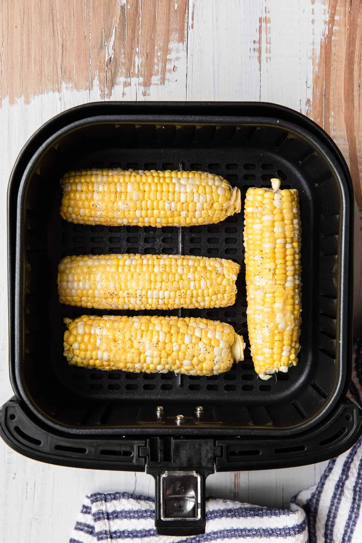 uncooked corn on the cob in an air fryer basket