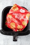 a bag of frozen waffle fries in an air fryer basket