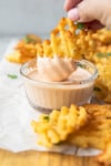 dipping a waffle fry into a pink dipping sauce