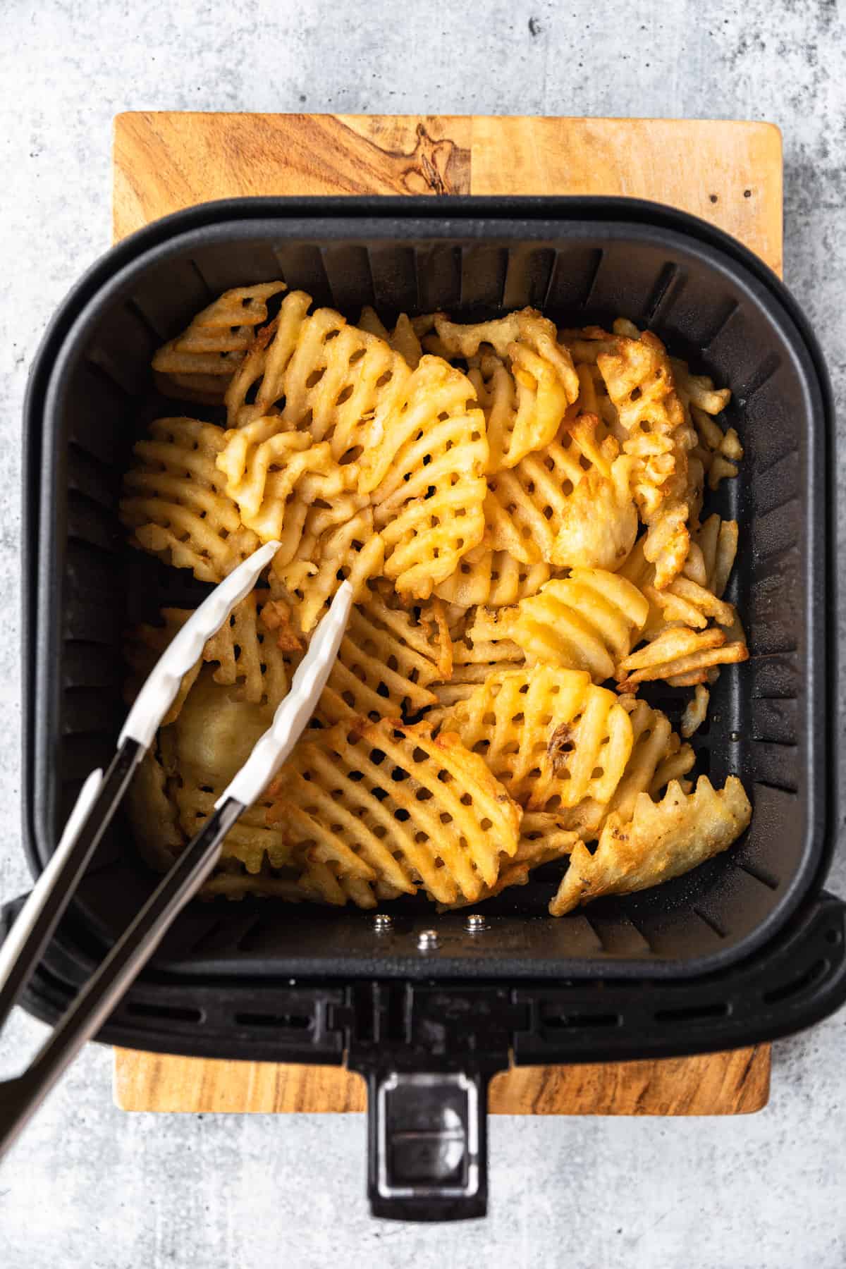 using tongs to turn fries over