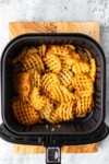 golden brown waffle fries in an air fryer basket