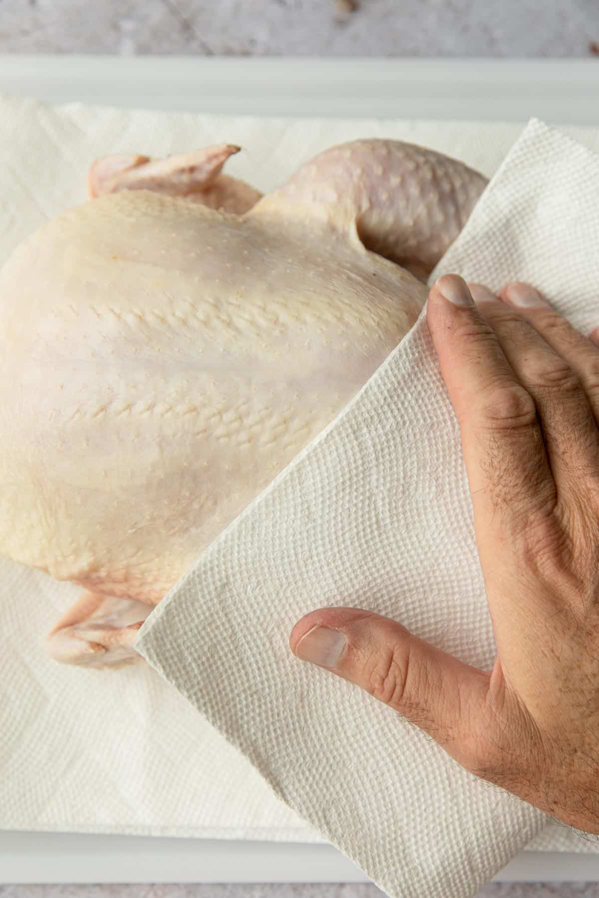 patting a raw chicken dry with paper towels