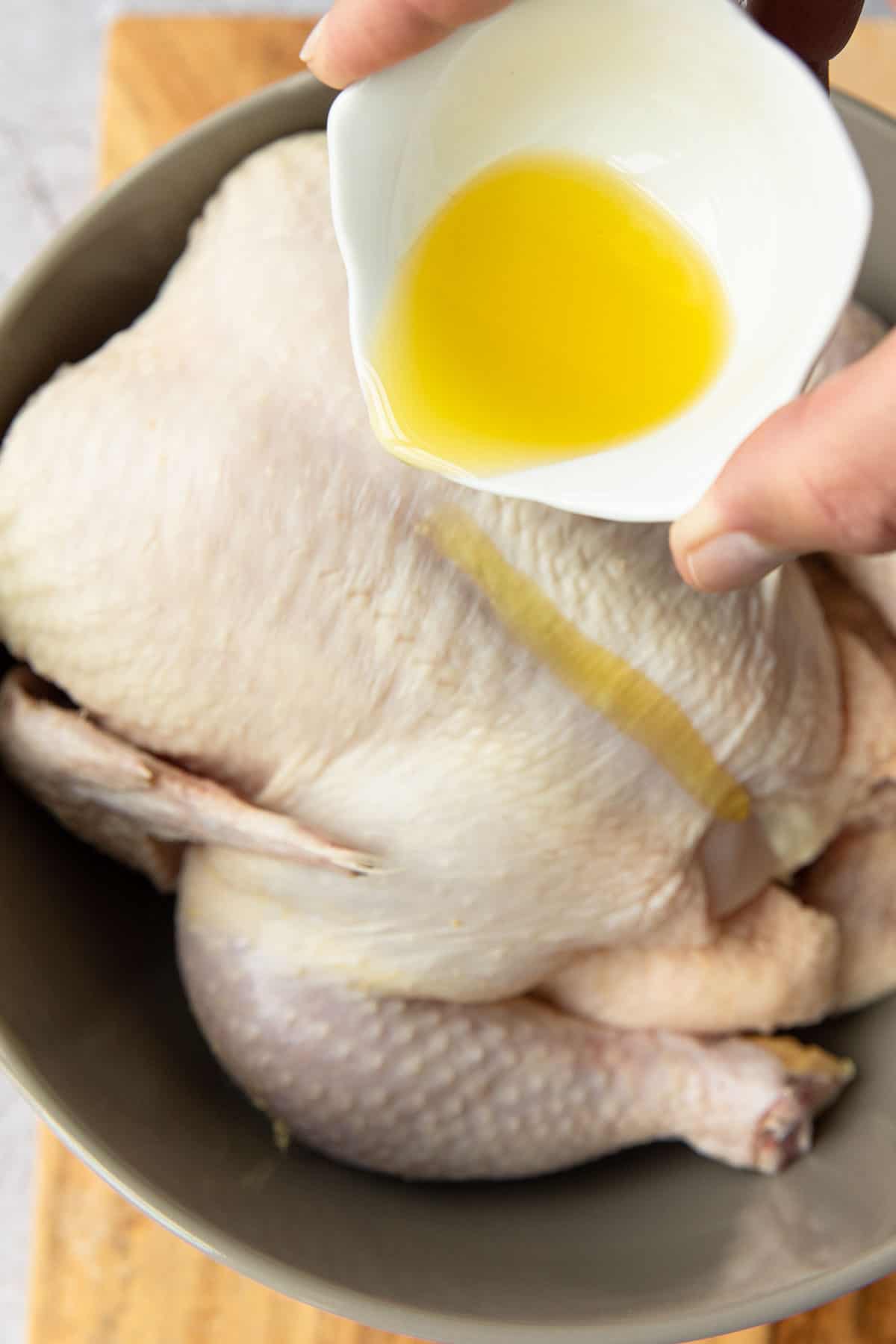 pouring olive oil over a raw chicken