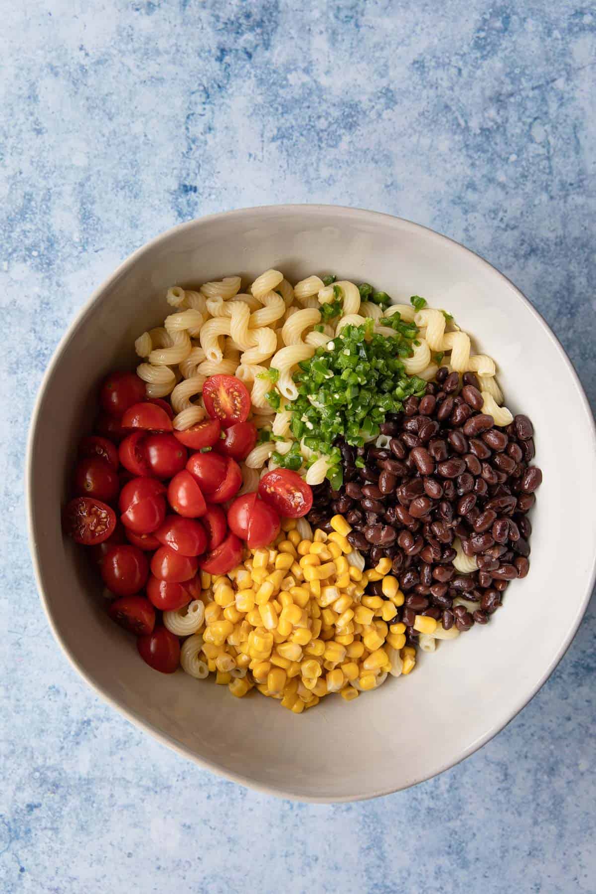 a bowl with pasta salad ingredients in sections