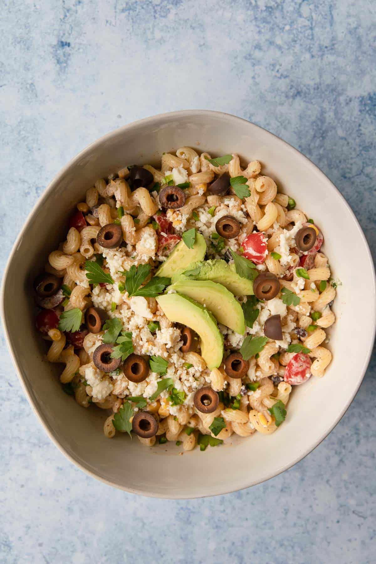 a bowl of pasta salad topped with sliced avocado