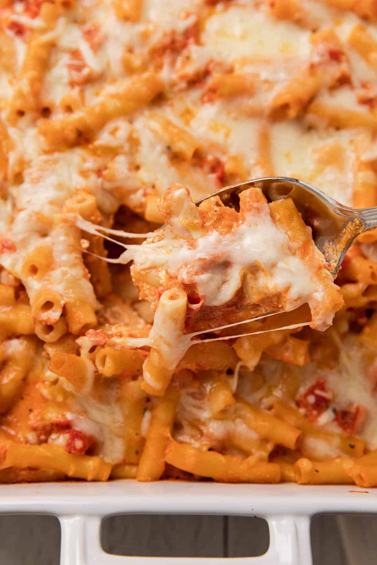 a casserole dish with a cheesy pasta dish being scooped out