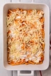 a casserole dish being layered with pasta, sauce and cheese