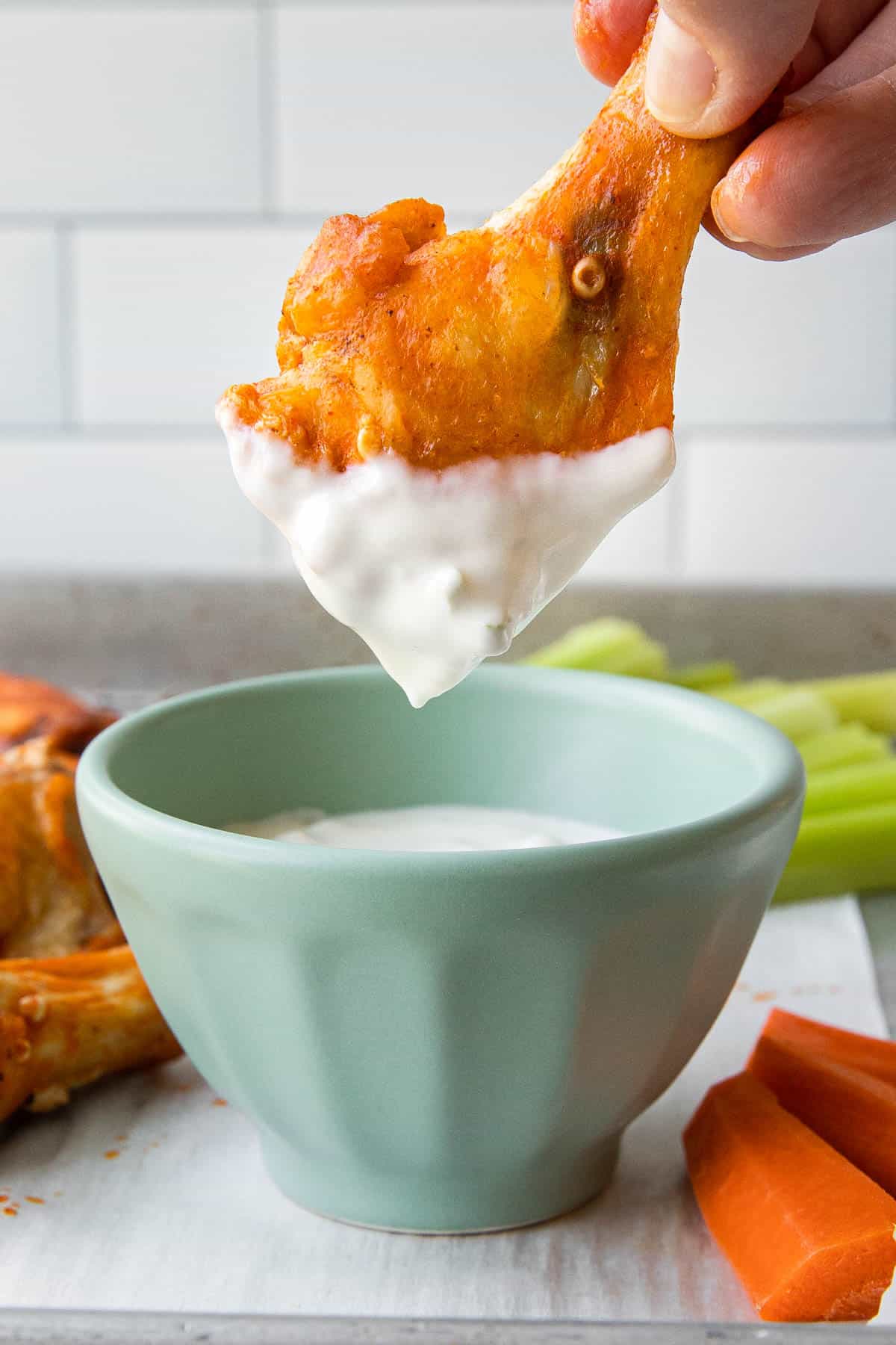 a crispy buffalo wing being dipped in a white dressing