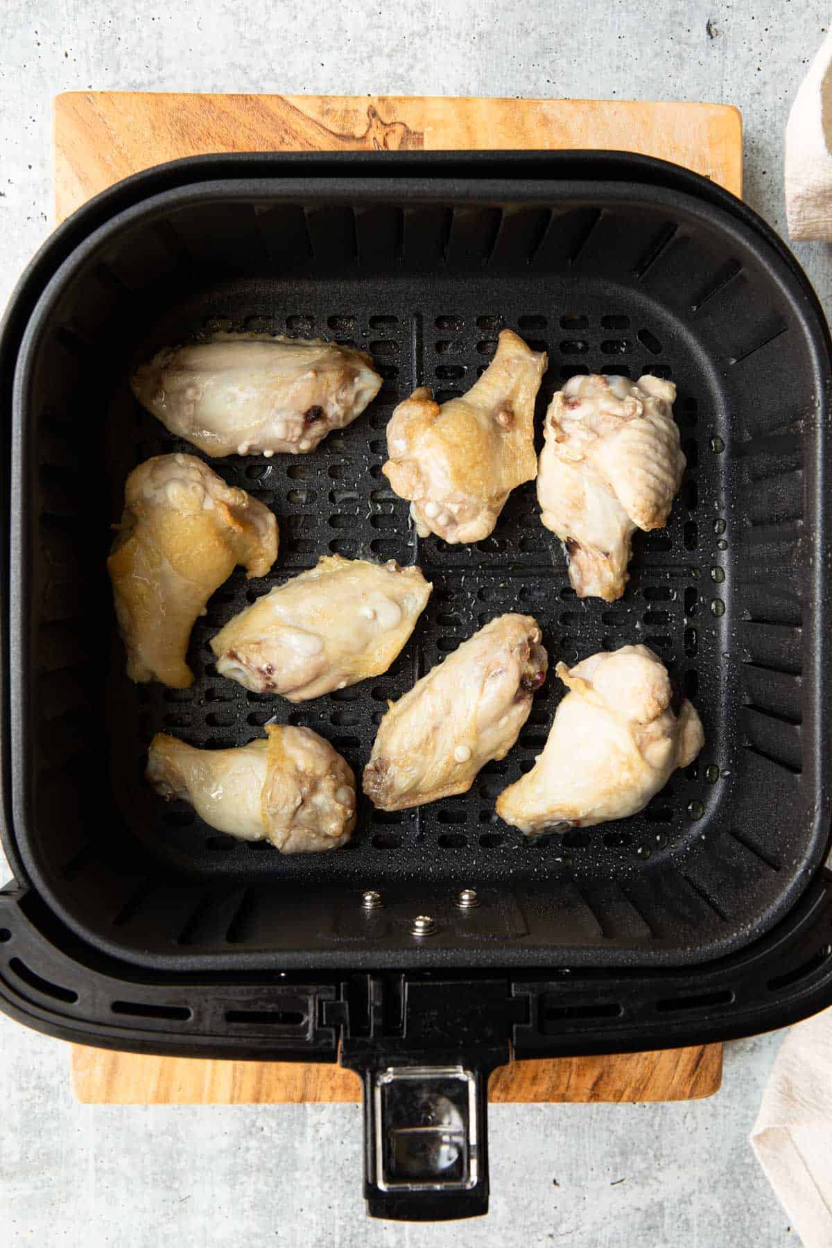 air fryer basket with raw frozen chicken wings