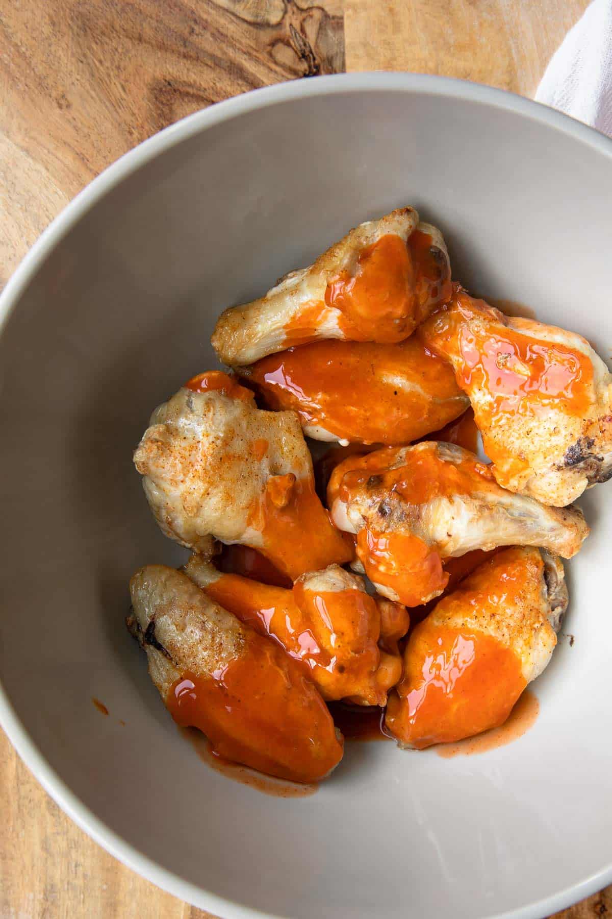 a bowl of cooked wings with buffalo sauce