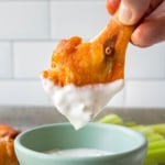 a buffalo chicken wing drum being dipped in a white dressing
