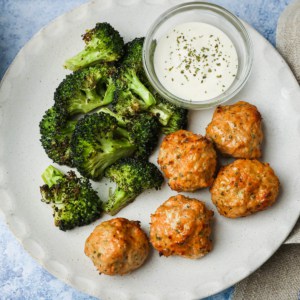 a plate of meatballs, broccoli, and a white dip