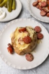 baked potato topped with sausage slices and sauerkraut
