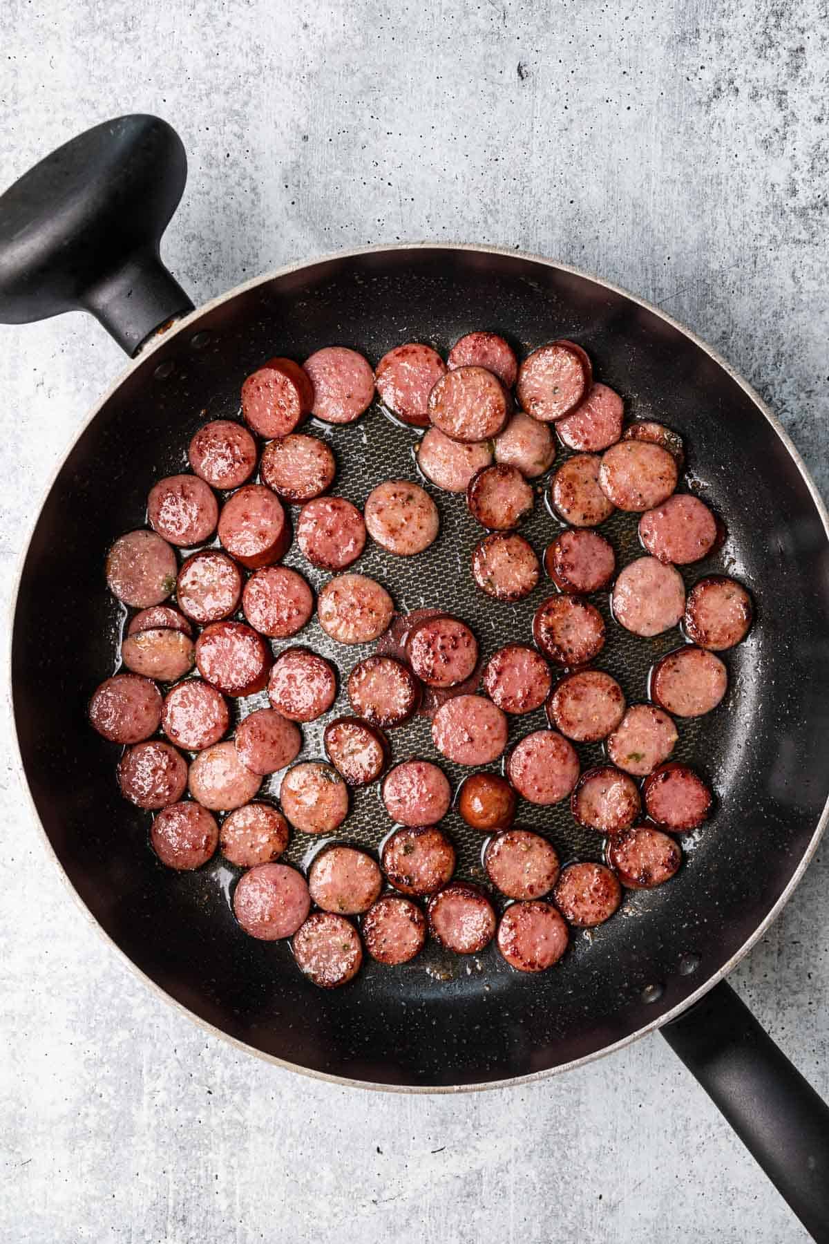 sliced kielbasa sausage being cooked in a skillet