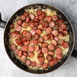 sliced kielbasa sausage in a skillet with sauerkraut