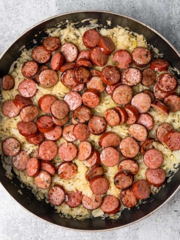 sliced kielbasa sausage in a skillet with sauerkraut