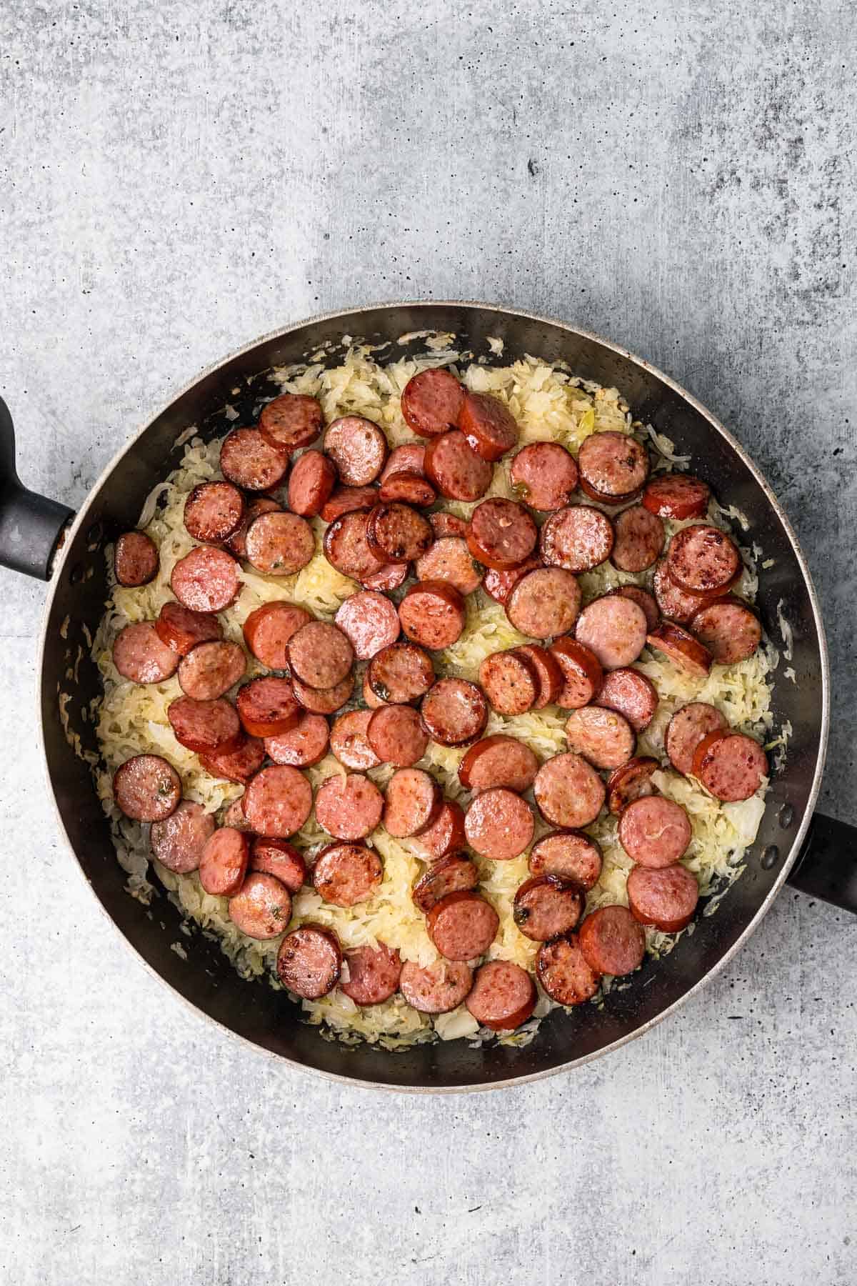 a skillet with sliced sausage and sauerkraut