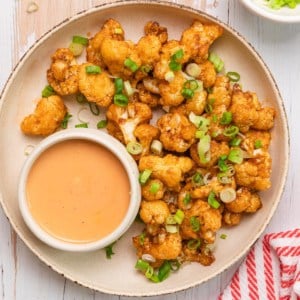 a plate of bang bang cauliflower with orange dipping sauce