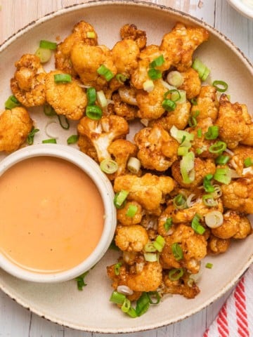 a plate of bang bang cauliflower with orange dipping sauce