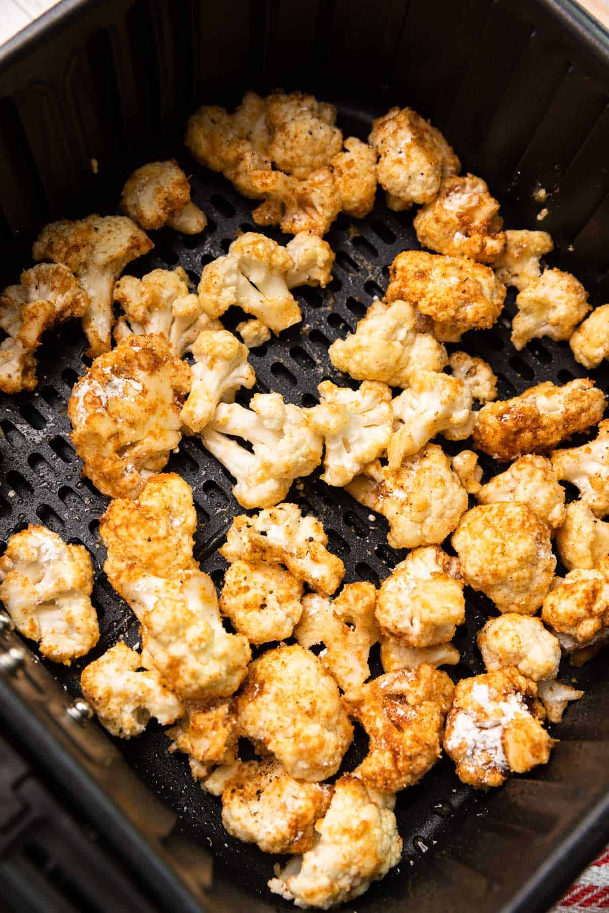 seasoned cauliflower florets in an air fryer basket