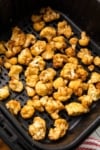 cooked cauliflower florets in an air fryer basket