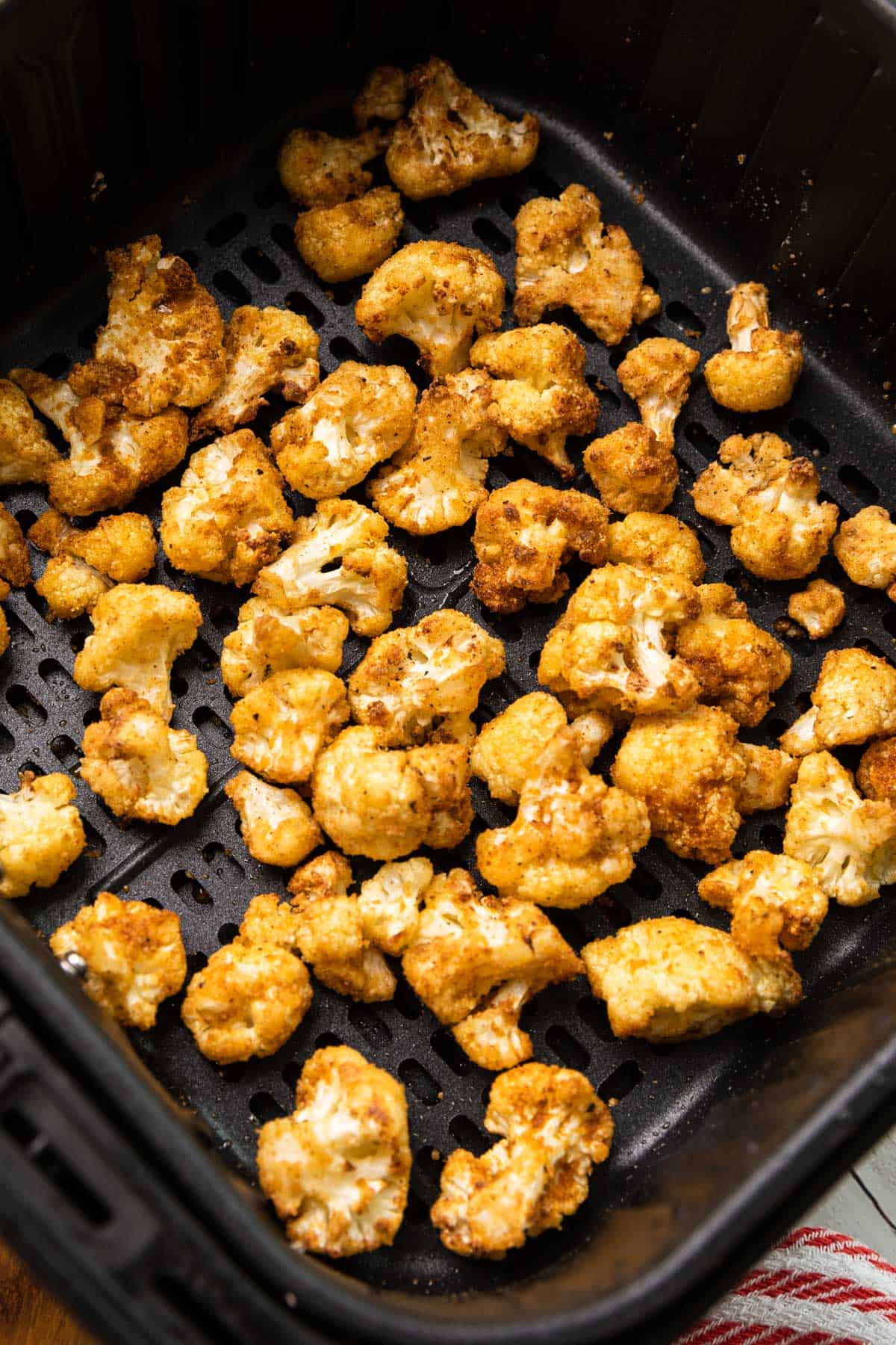 cooked cauliflower florets in an air fryer basket