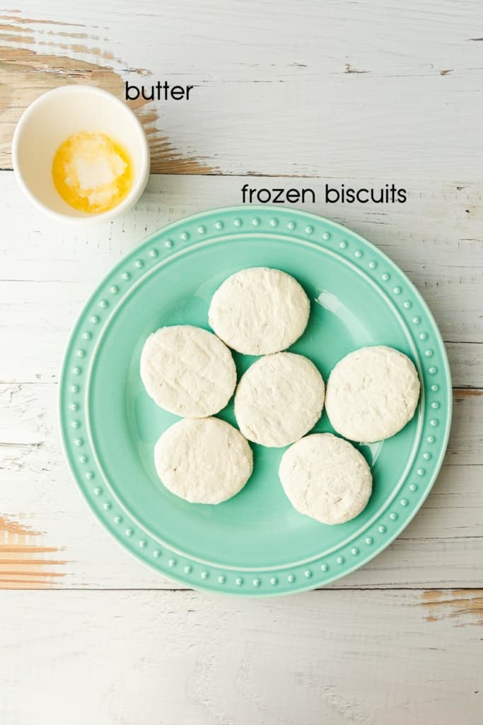 a green plate with uncooked frozen biscuits