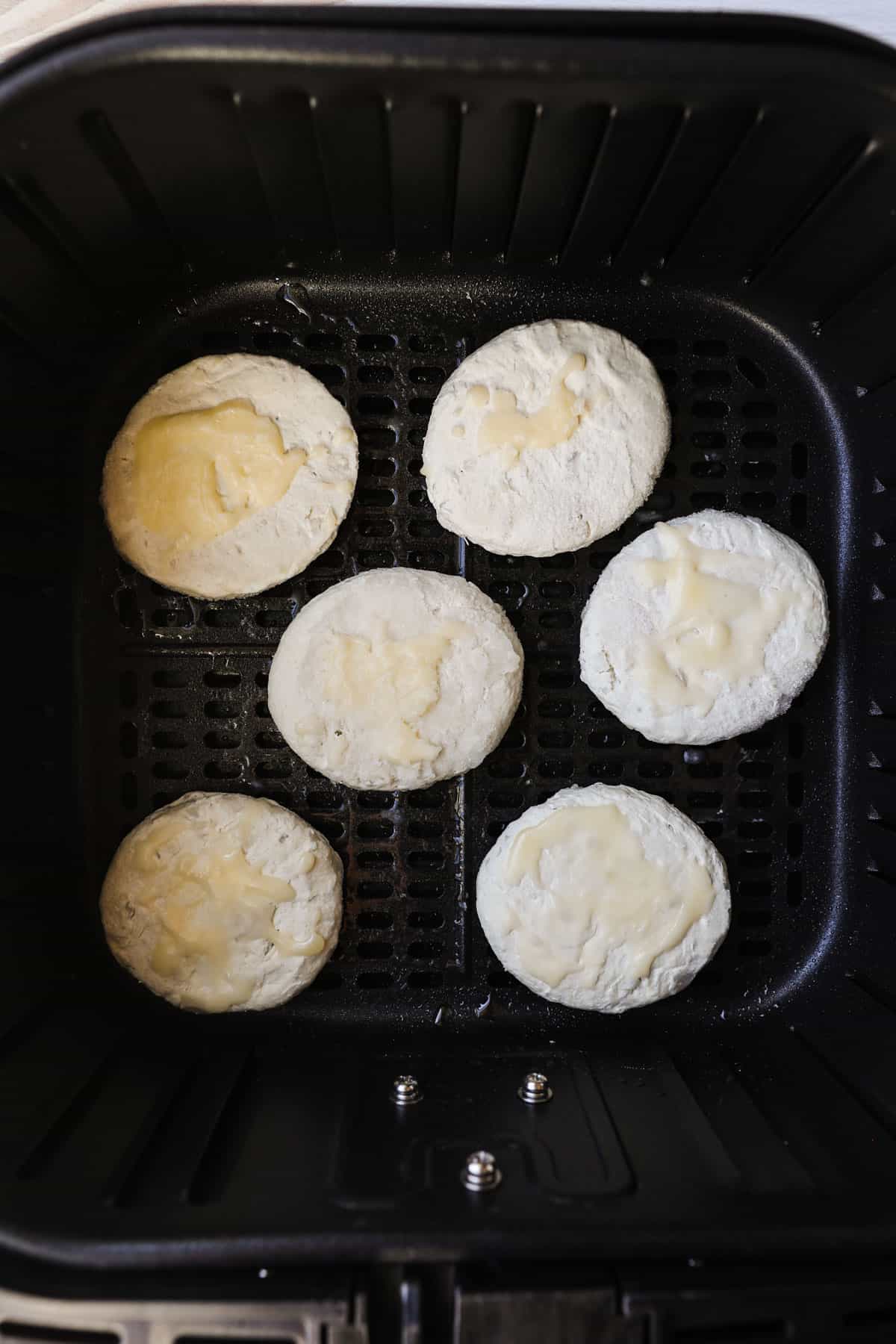 Frozen biscuits in the air fryer basket.