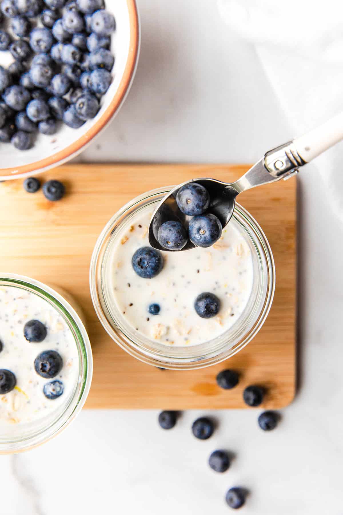 adding fresh blueberries to a glass of oatmeal