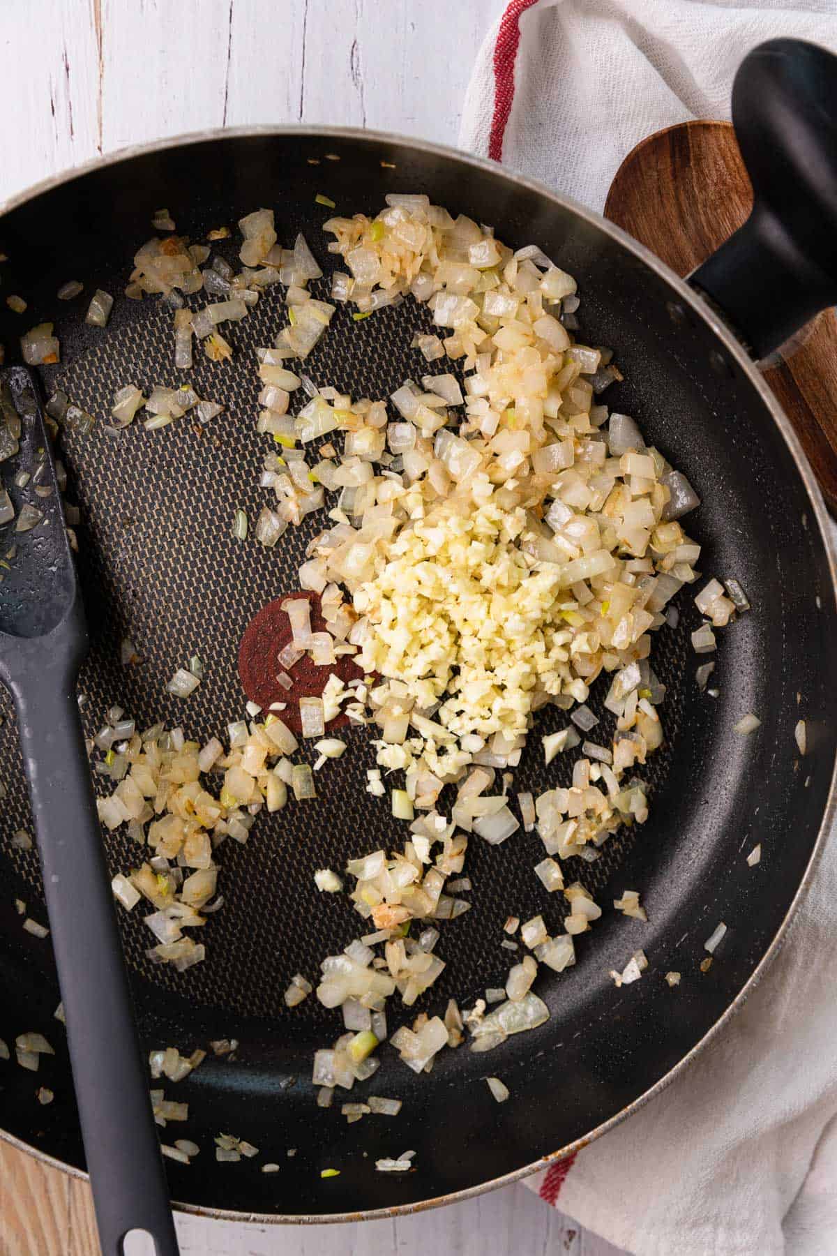 a skillet with onions and garlic cooking