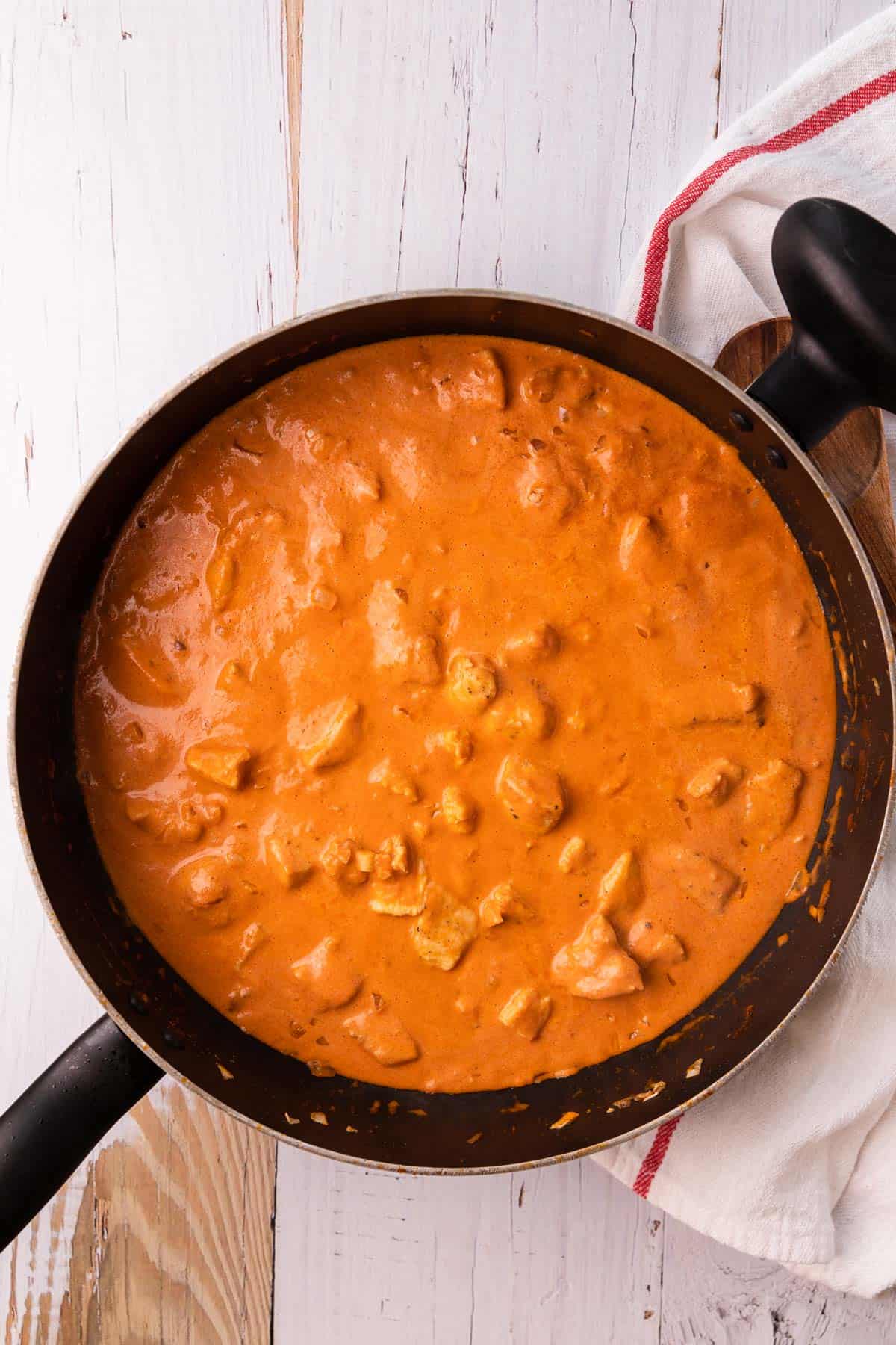 a skillet with cooked chicken in a tomato sauce