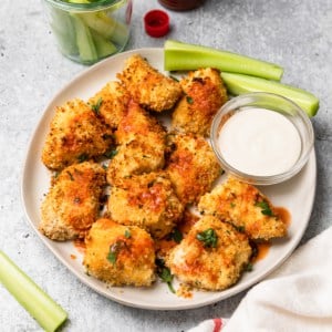 a plate of chicken bites with some hot sauce dabbed on