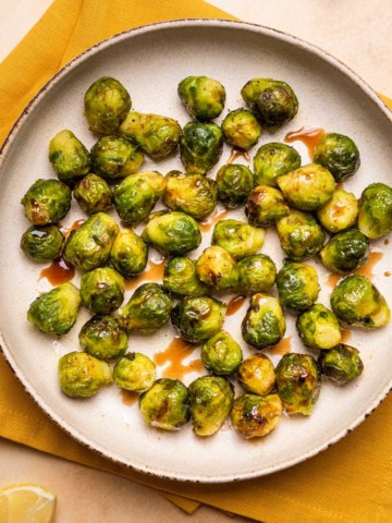 a plate of air fryer brussels sprouts with balsamic glaze drizzled over