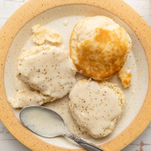 a plate of biscuits smothered in white bacon cream gravy