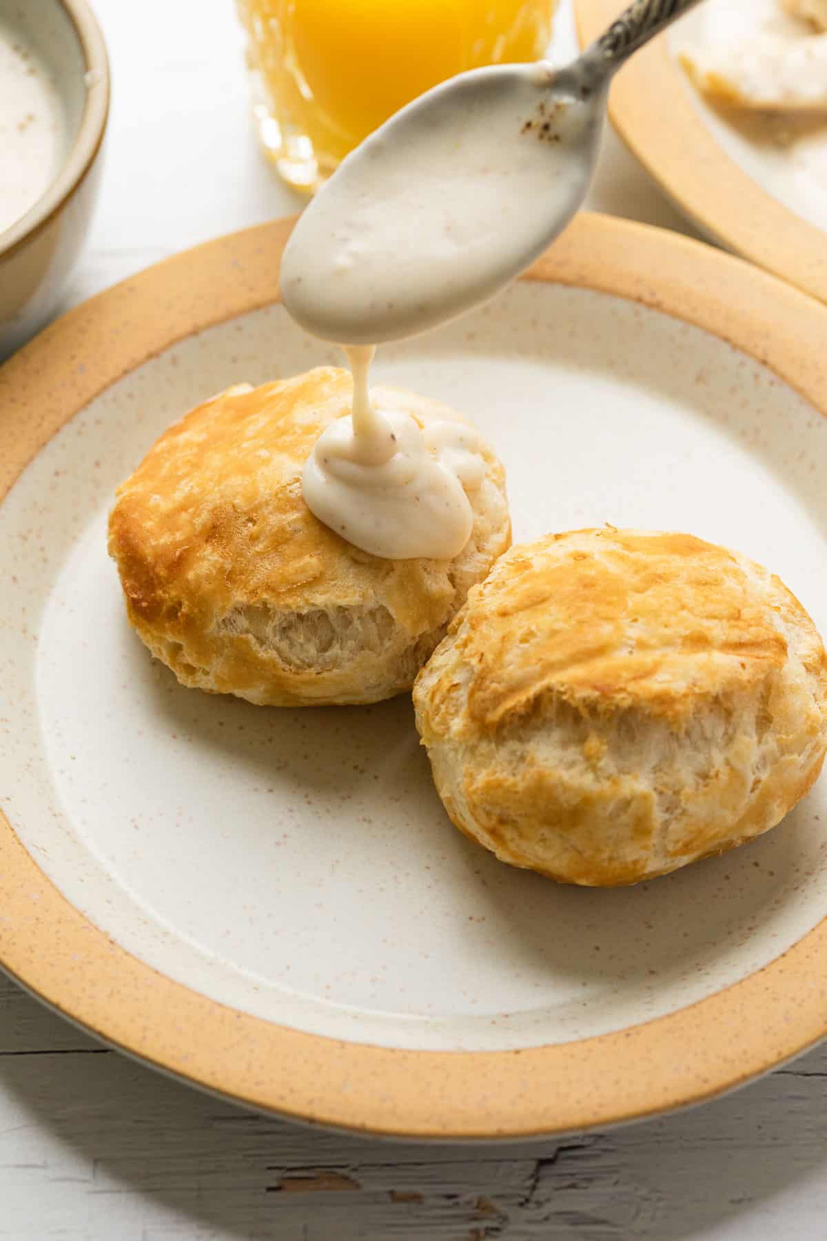 spooning white cream gravy over biscuits