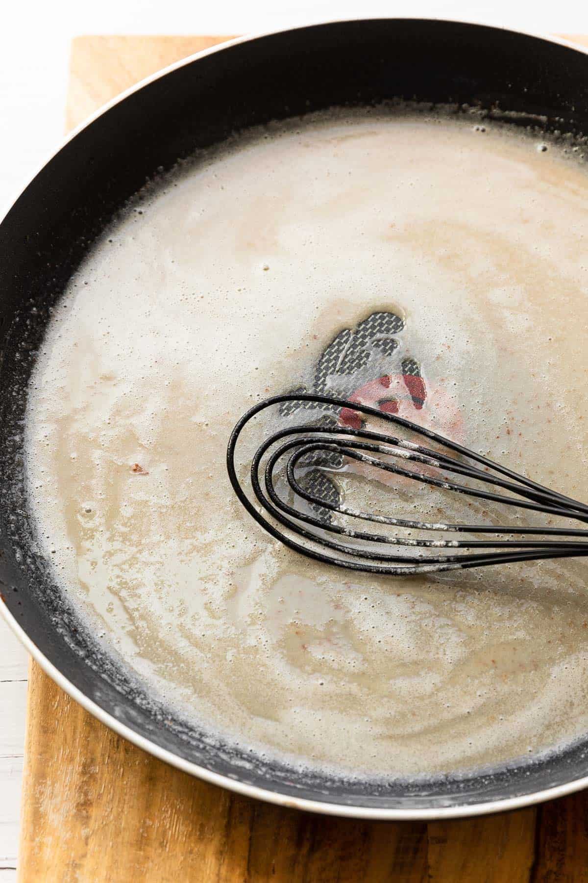 Whisking flour into bacon drippings.