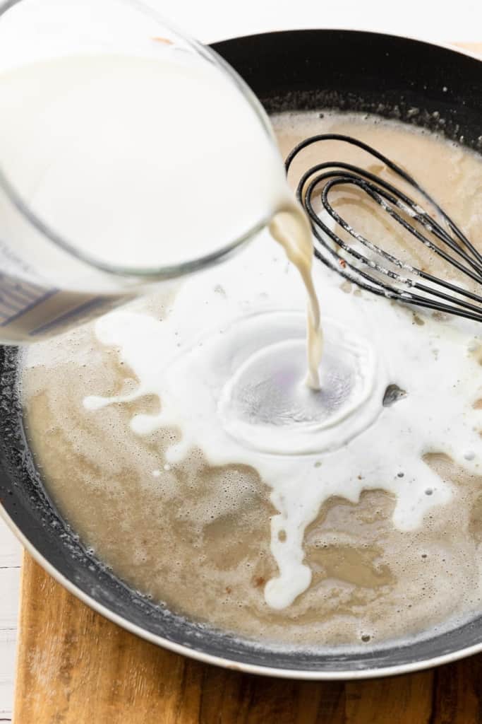 Adding milk to make a white gravy.