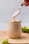 chipotle crema oozing off a spoon into a jar