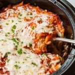 Crockpot baked ziti in a slow cooker with a scoop being served.