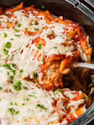 Crockpot baked ziti in a slow cooker with a scoop being served.