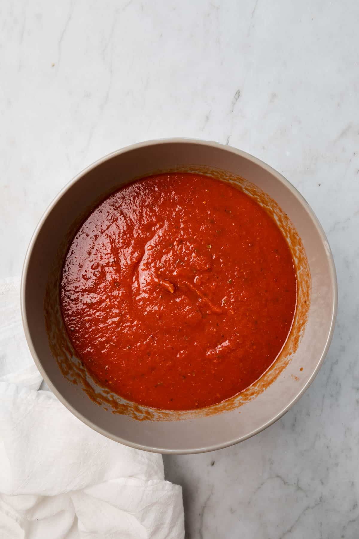 Combining tomato and mariana sauces in a bowl.