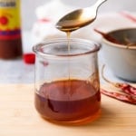 hot honey sauce being drizzling off a spoon into a glass jar