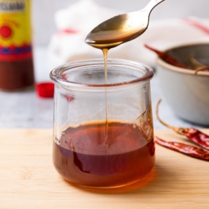 hot honey sauce being drizzling off a spoon into a glass jar