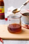 hot honey sauce drizzling off a spoon into a glass jar