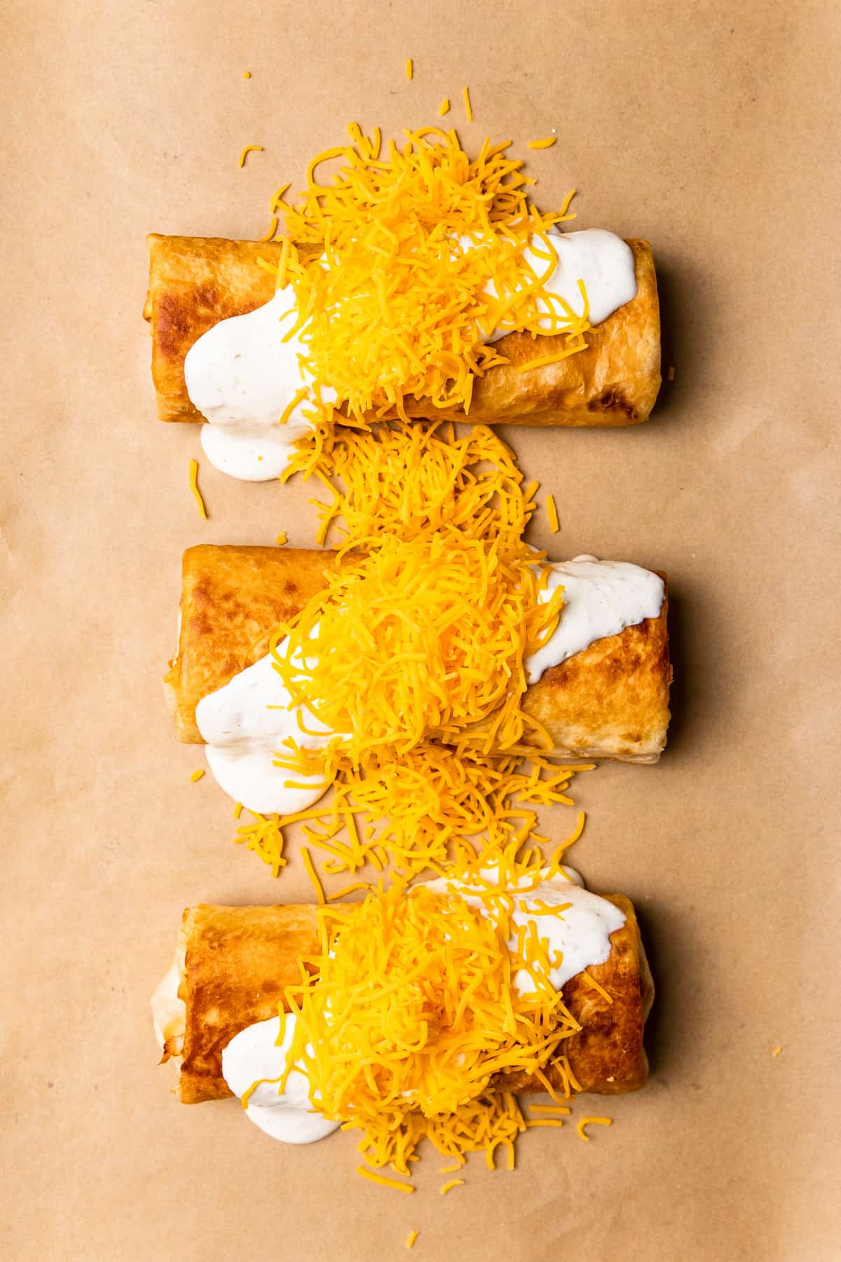 Topped chimichangas with sauce and shredded cheese