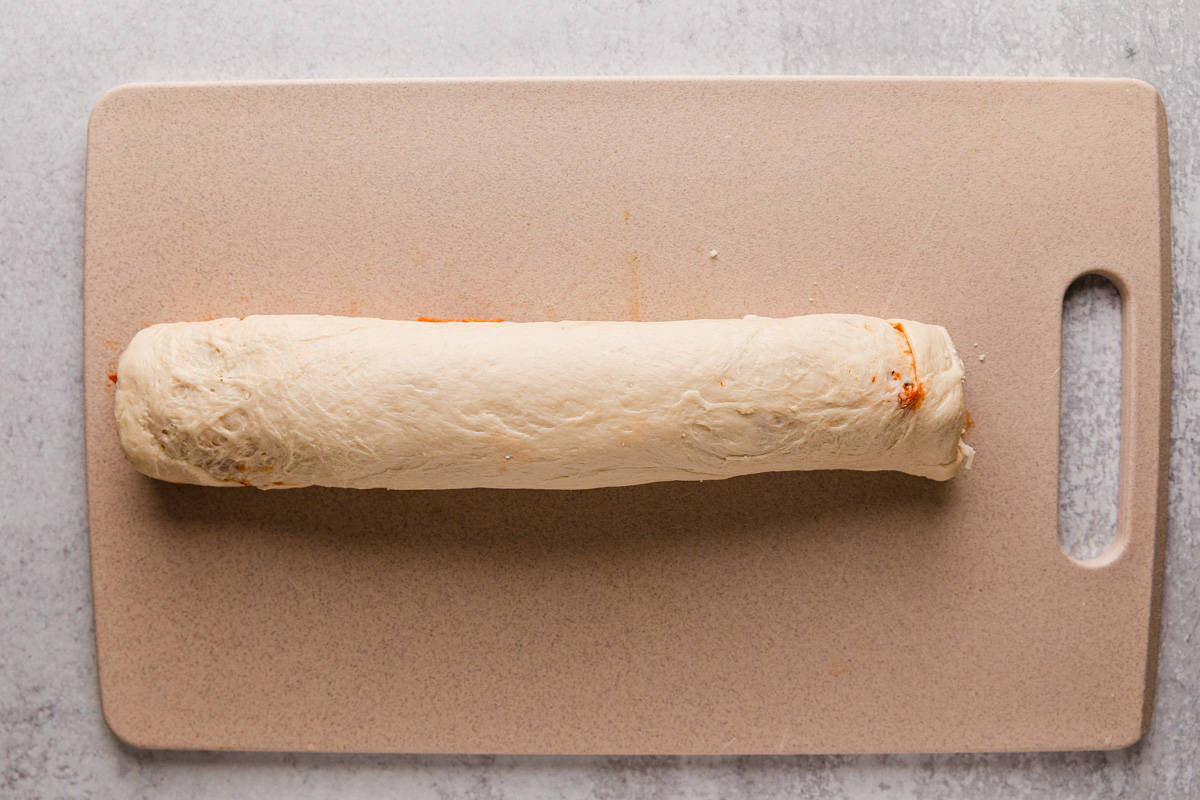 rolling up pizza dough into a log