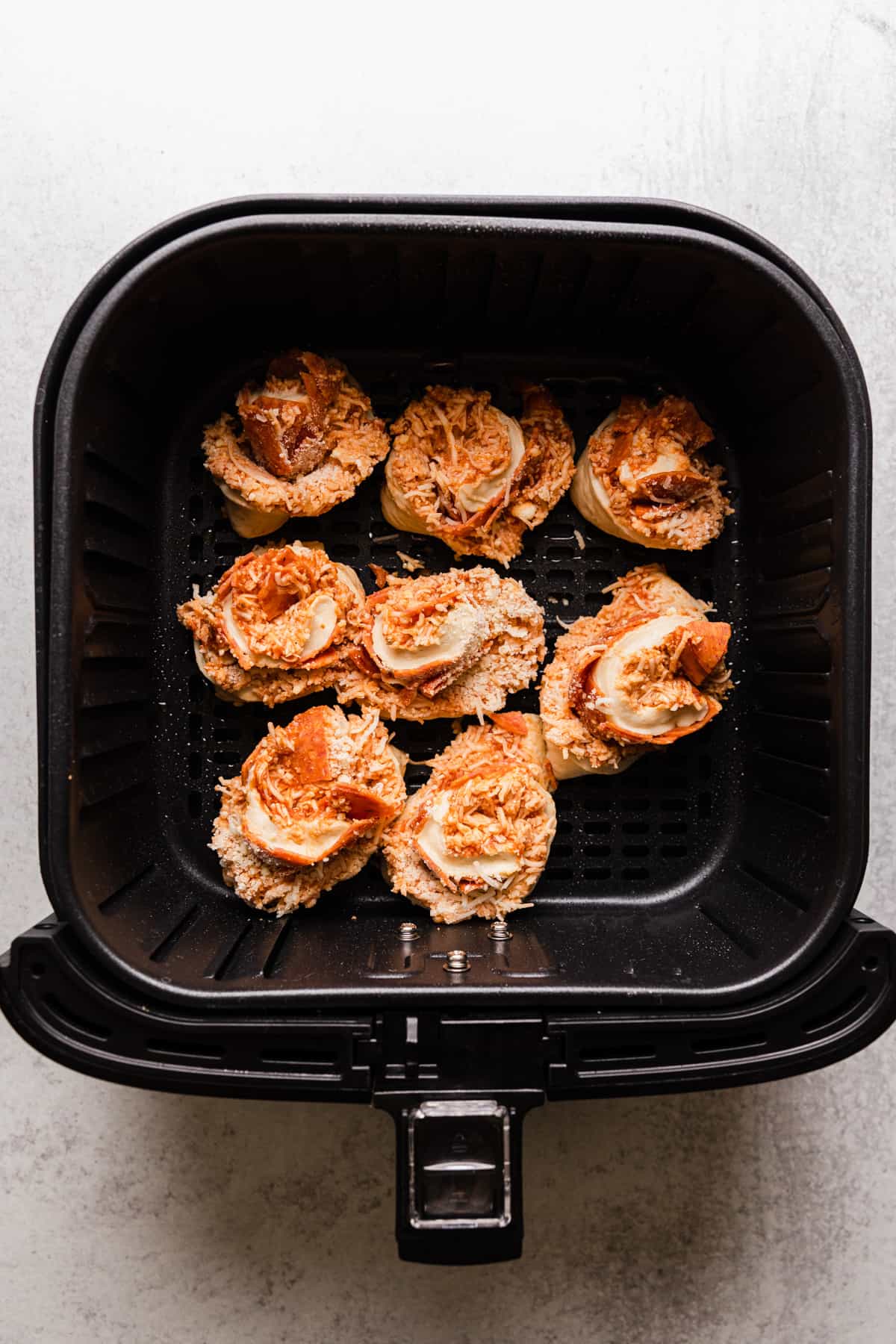 pizza rolls in an air fryer basket before