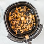 an air fryer basket with cooked mushroom slices